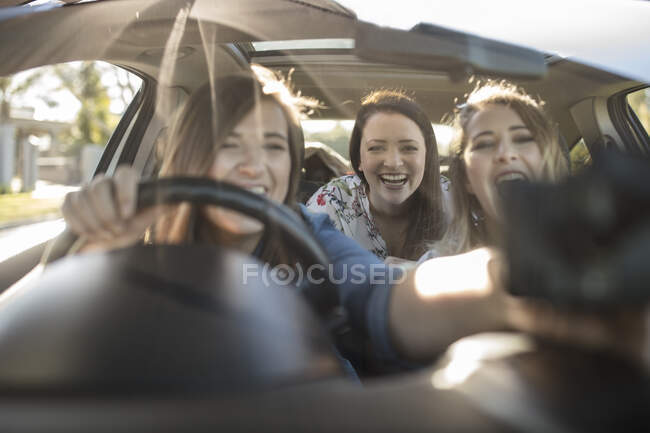 Drei junge Frauen im Auto, Fahrer stellt Navi auf Fenster — Stockfoto