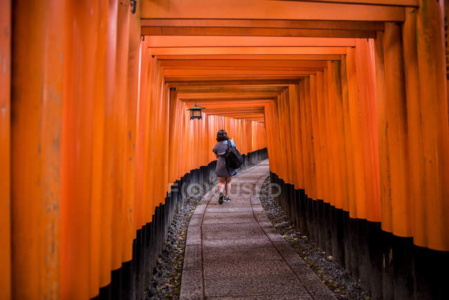 Mujer caminando en Torii Gates, Santuario Fushimi Inari, Kyoto, Japón - foto de stock