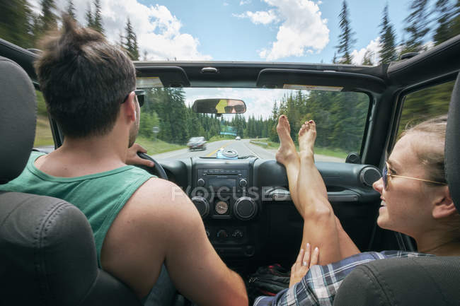 Jovem mulher com os pés para cima dirigindo em viagem de carro com namorado, Breckenridge, Colorado, EUA — Fotografia de Stock
