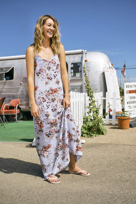 Young woman in maxi dress laughing by airstream coffee shop — Stock Photo