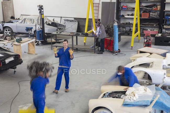Equipo mecánico de coches en movimiento y ocupado en el garaje de reparación - foto de stock