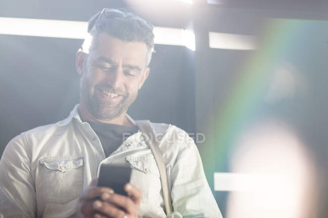 Hombre adulto sonriendo y usando smartphone - foto de stock