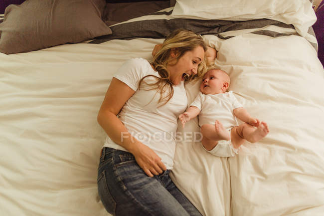 Overhead view of woman and baby daughter lying on bed — Stock Photo