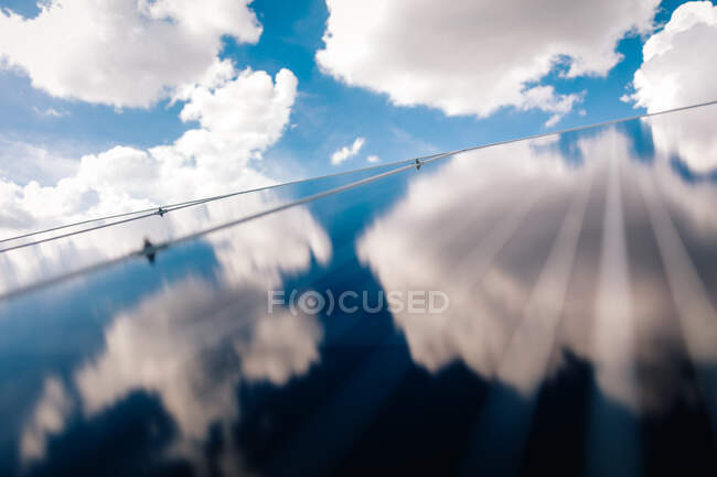 Solar panels on roof, reflecting clouds in blue sky — Stock Photo