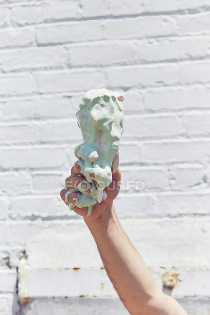 Man holding up melting, dripping ice cream cone, close up of hand — Stock Photo