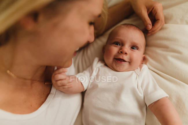 Portrait of woman and baby daughter lying on bed — Stock Photo