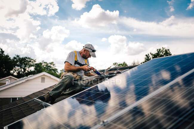 Працівник встановлює сонячні панелі на даху будинку — стокове фото
