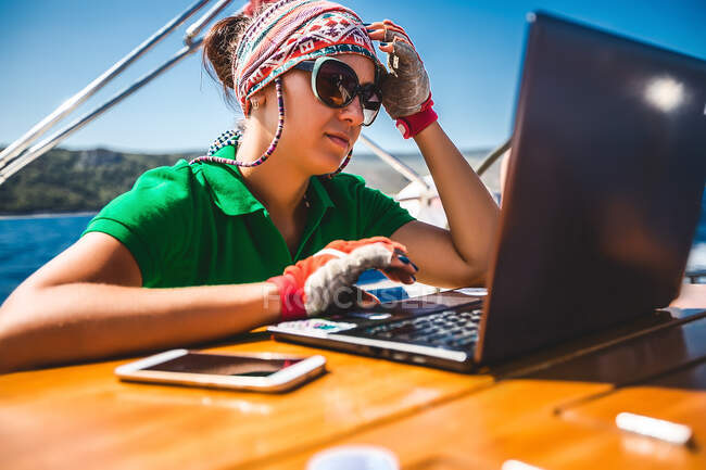 Молодая женщина смотрит на ноутбук на борту яхты возле побережья, Хорватия — стоковое фото