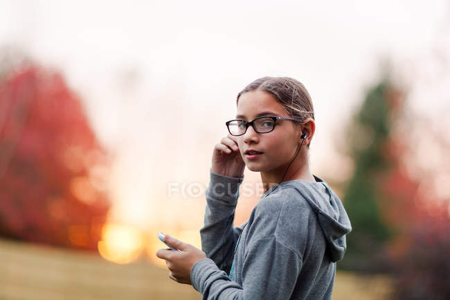 Porträt eines Mädchens mit Kopfhörern und Smartphone im Garten — Stockfoto