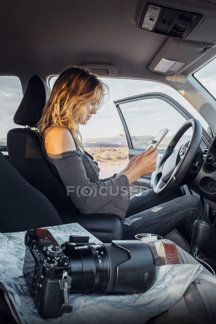 Young woman sitting in car with digital tablet, Mexican Hat, Utah, USA — Stock Photo