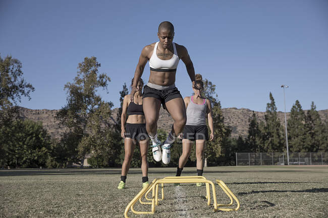Woman jumping over agility hurdles — Stock Photo