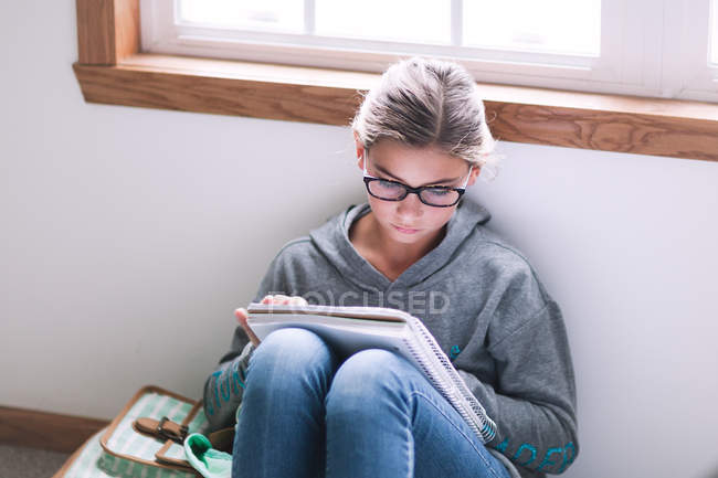 Дівчина сидить на підлозі і пише домашнє завдання — стокове фото