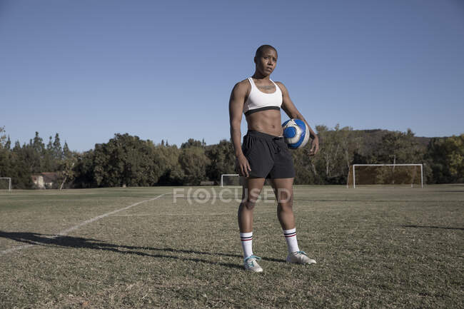 Porträt einer Frau, die Fußball hält und in die Kamera blickt — Stockfoto