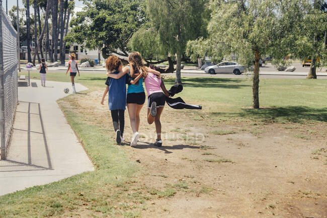 Rear view of girls and teenage schoolgirls running on school playing field — Stock Photo