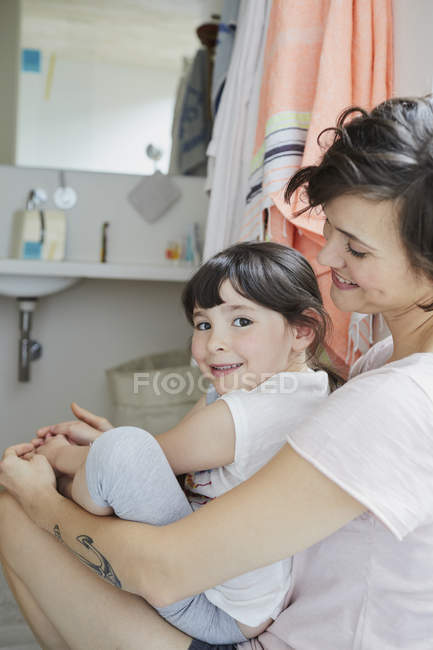 Mãe e filha sentadas juntas no banheiro — Fotografia de Stock