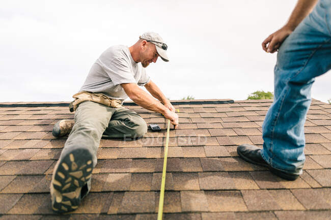 Two workmen on roof, preparing to install solar panels, low angle view — Stock Photo
