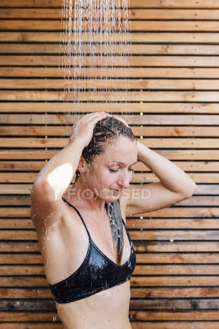 Молодая женщина моет волосы в душе на открытом воздухе — стоковое фото
