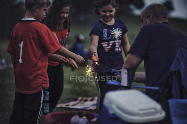 Батько запалює блискавки для групи дітей — стокове фото