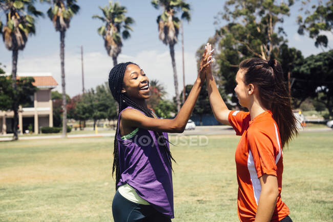 Duas alunas adolescentes futebol high fiving no campo de esportes da escola — Fotografia de Stock