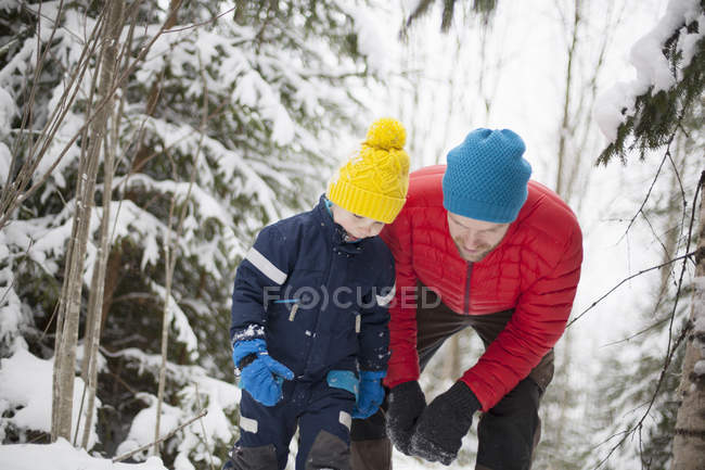 Homem e filho olhando para baixo na floresta coberta de neve — Fotografia de Stock