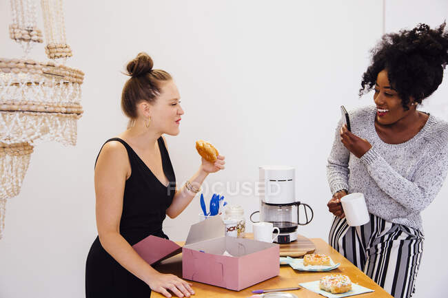 Женщина фотографирует друга, поедающего пончик — стоковое фото