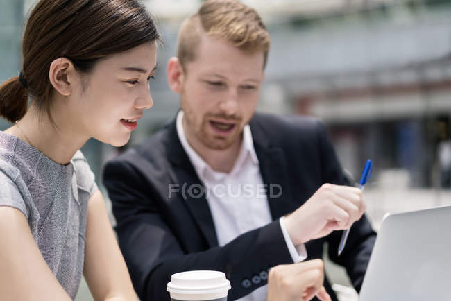 Colleagues looking at laptop at sidewalk cafe — Stock Photo
