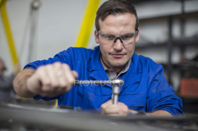 Male car mechanic using wrench in repair garage — Stock Photo
