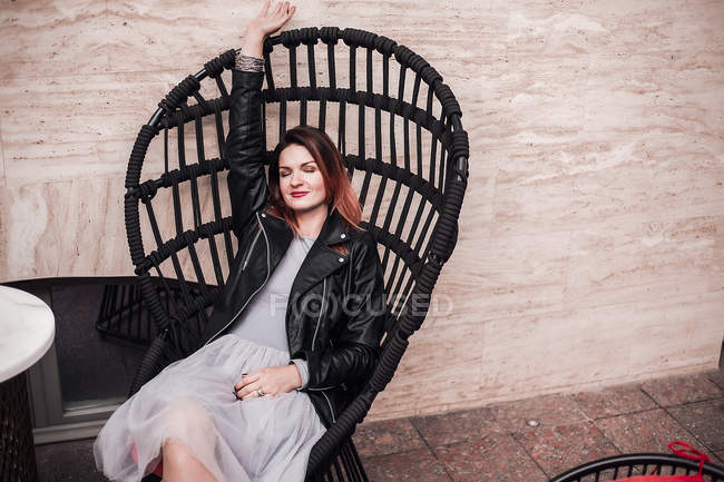 Portrait of woman sitting in chair with arm raised — Stock Photo
