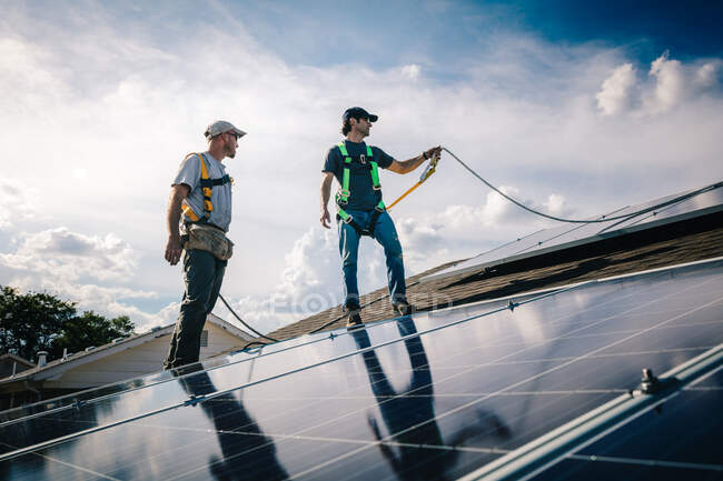 Deux ouvriers installant des panneaux solaires sur le toit de la maison, vue à angle bas — Photo de stock