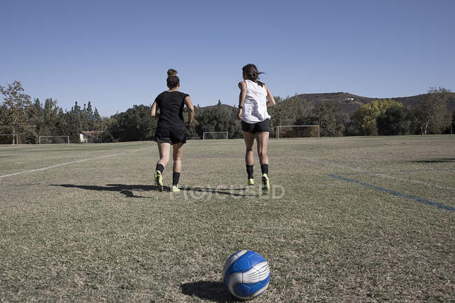 Dos mujeres corriendo en el campo de fútbol - foto de stock