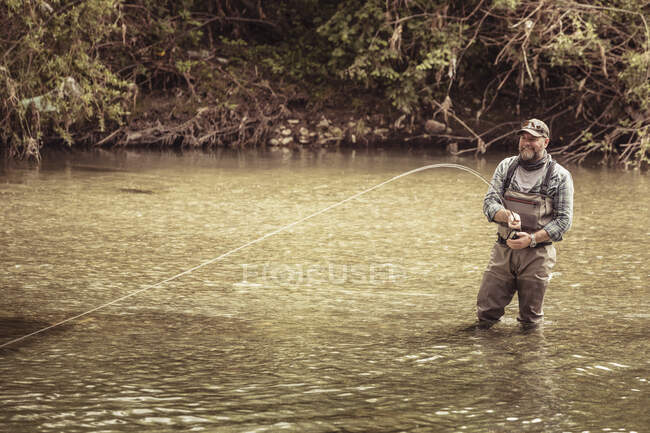Maduro pescador rodilla de pesca en el río, Mozirje, Brezovica, Eslovenia - foto de stock