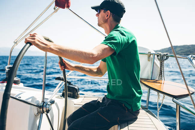 Mezzo barca sterzo uomo adulto vicino alla costa, Croazia — Foto stock