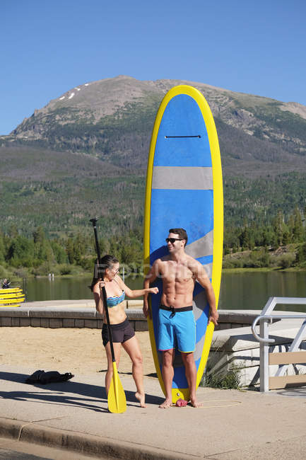 Paddleboarding couple with paddleboard on lake shore, Frisco, Colorado, USA — Stock Photo