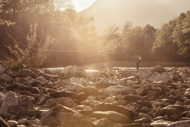 Pêcheur coulant ligne de pêche dans la rivière ensoleillée, Mozirje, Brezovica, Slovénie — Photo de stock