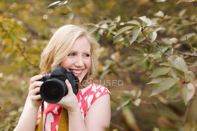 Jeune femme utilisant la caméra dans le parc — Photo de stock