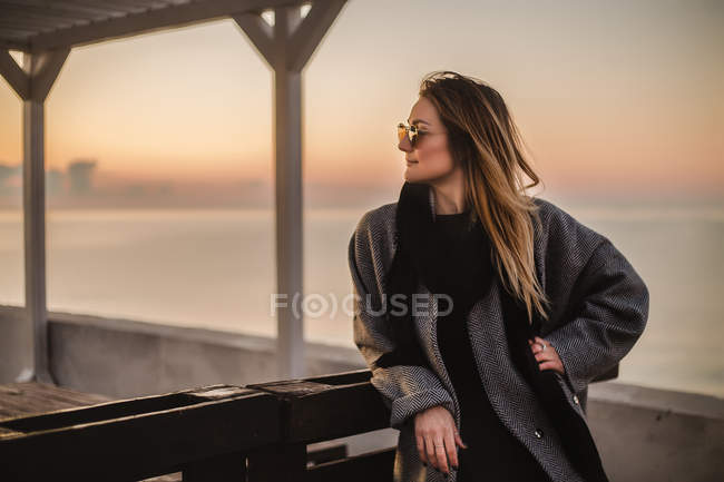 Retrato de mujer con abrigo de invierno y gafas de sol mirando hacia otro lado - foto de stock