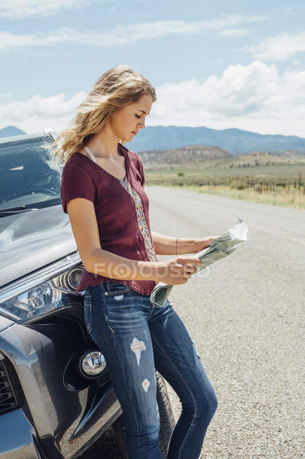 Vista lateral de la mujer en coche mirando el mapa - foto de stock