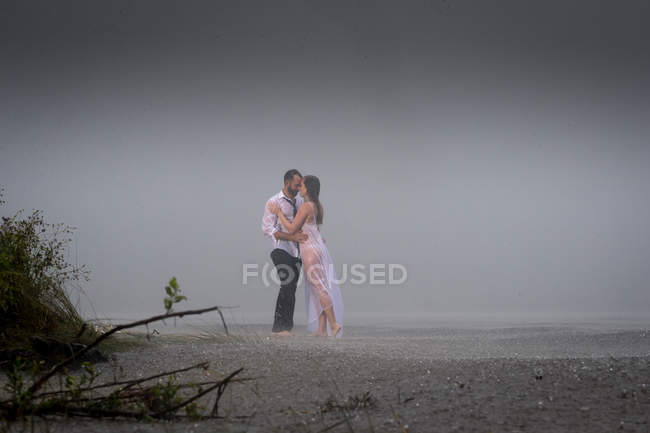Nasses romantisches Paar am nebligen Strand — Stockfoto