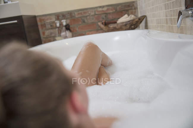 Jeune femme allongée dans un bain moussant — Photo de stock