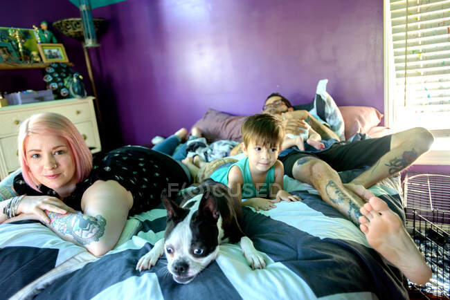 Famiglia e cane domestico sul letto in camera da letto — Foto stock