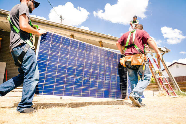 Workmen carrying solar panels, preparing for installation, low angle view — Stock Photo