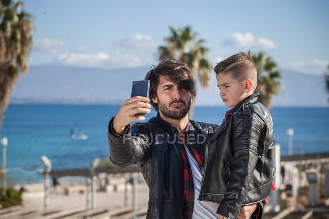 Pai e filho tomando selfie ao ar livre — Fotografia de Stock