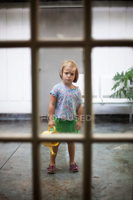 Girl with watering can standing stubbornly still — Stock Photo