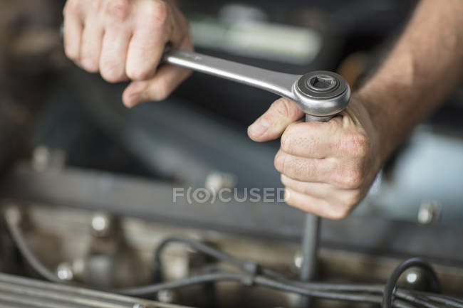 Mãos de mecânico masculino usando chave na garagem de reparação — Fotografia de Stock