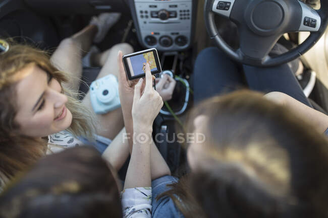 Tres mujeres jóvenes en coche, mirando navegación por satélite, vista aérea - foto de stock