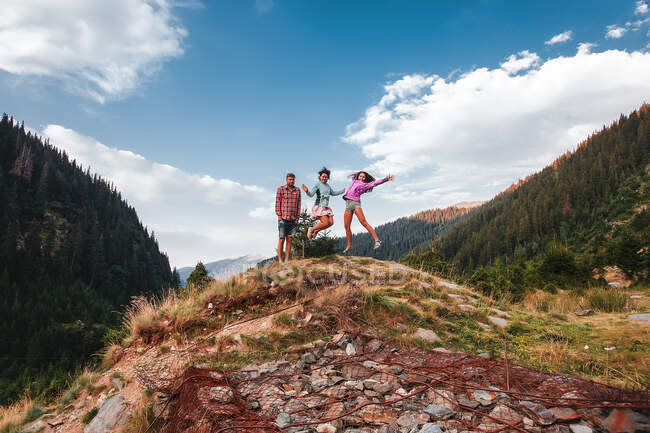 Portrait of man and young women jumping mid air in mountain landscape, Draja, Vaslui, Romania — Stock Photo