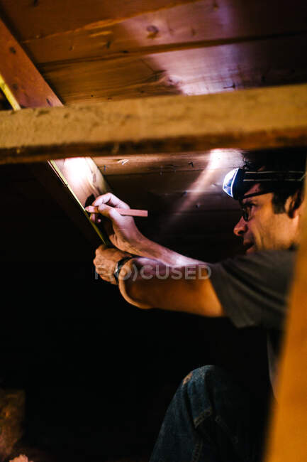Electrician measuring beams in loft — Stock Photo