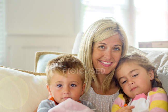 Mulher adulta média com filha e filho criança no sofá, retrato — Fotografia de Stock