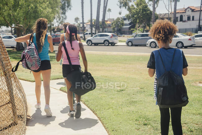 Écolières marchant à la pratique du football sur le terrain de sport scolaire — Photo de stock