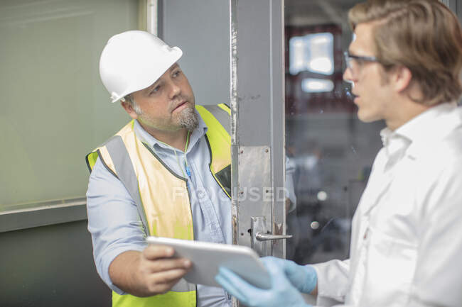 Workman and lab worker in thread factory, holding digital tablet — Stock Photo